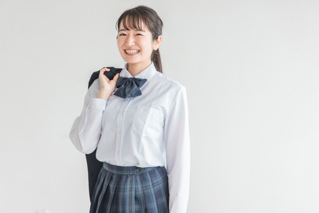 女子高生がカバンを持って笑っている様子